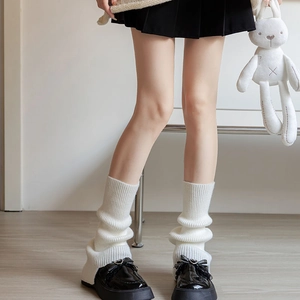 Close-up of white knitted leg warmers with vertical rib texture and chunky loafers