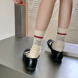 Detailed texture of off-white ribbed wool socks with wine red stripes and logo label