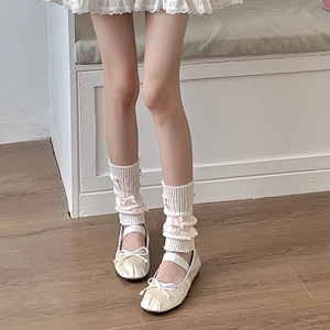 Détail de jambières en tricot blanc avec nœuds roses dans un style Balletcore