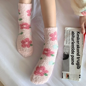 Dettaglio di calzini in pile corallo rosa con motivi floreali rossi per l'inverno