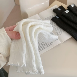 Detail of ribbed knit leg warmers showing wavy edge trim and soft texture in hand