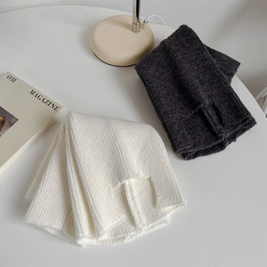 Detailed knit texture of white and dark grey leg warmers with ribbed design and heel slit