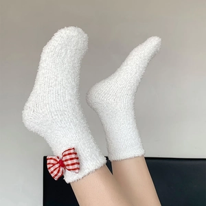Detailed view of plush coral fleece socks with a cute red gingham bow decoration