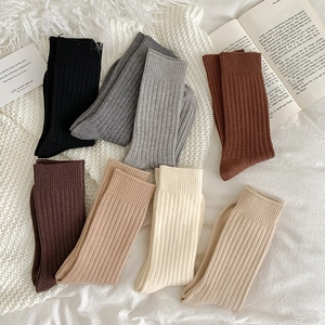 Flachbild von warmen gerippten Socken in acht neutralen Erdtönen auf einer Strickdecke