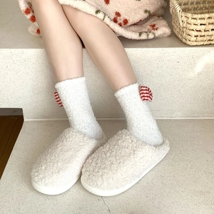 Detail of coral fleece socks with red checkered bows and matching plush slippers