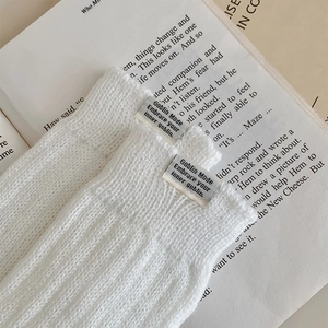 Detail of white ribbed knit leg warmers featuring a grey Goblin Mode woven label