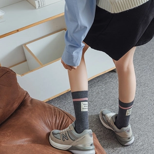 Detail of dark grey wool socks with pink stripes and fabric tag paired with sneakers