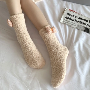 Detail of coral fleece winter socks with orange plaid bow on a cozy white background