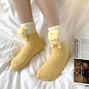 Detail of plush coral fleece socks featuring a 3D cartoon cat and warm fuzzy texture