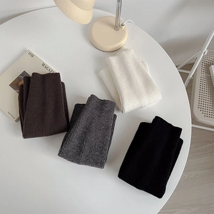 Close-up of four colors of ribbed knit leg warmers in black, white, grey, and coffee
