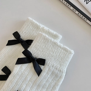 Gros plan détaillé de jambières en tricot blanc avec des nœuds noirs en ruban doux