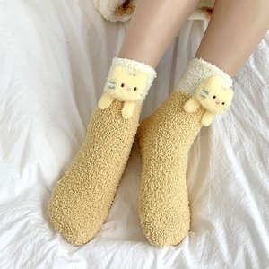 Close-up of cozy coral fleece socks with cute cat doll decoration on white bedding