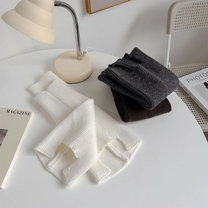 Multi-color ribbed knit leg warmers in white, dark grey and brown on a cozy chair