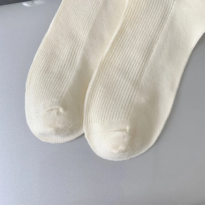 Macro shot of cream white ribbed knit wool socks showing high density fabric texture