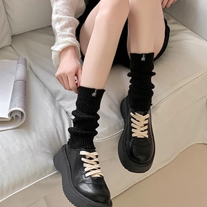 Japanese style black knit slouch socks with platform loafers on feet in studio setting