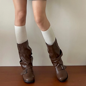 Close-up of retro brown slouchy mid-calf boots with decorative silver buckles