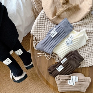 Detail of assorted rib-knit crew socks with woven labels on a wooden table