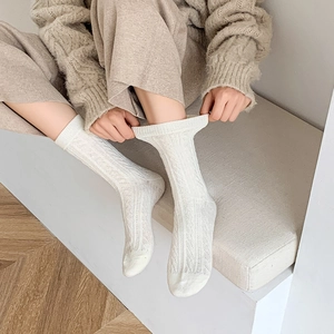 Detailed view of cable knit pattern on thick cream-colored thermal mid-calf crew socks