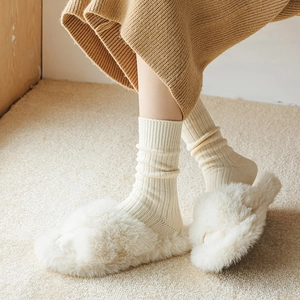 Nahaufnahme von weichen Wintersocken mit Rippenstruktur und flauschigen Hausschuhen