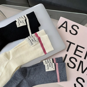 Detailed view of ribbed wool socks in black, cream and grey with minimalist cloth labels