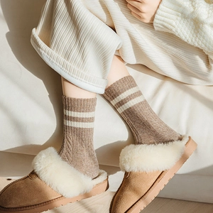 Close-up of thick striped wool socks with fleece-lined suede slippers and corduroy pants
