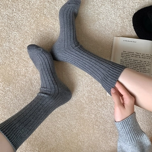 Nahaufnahme grauer gerippter Wintersocken in gemütlicher Heimkulisse mit einem Buch