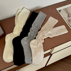 Flat lay of four pairs of ribbed cotton knee-high socks in neutral tones on a wood surface