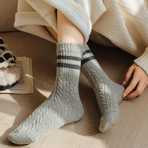 Detailed knit texture of gray wool socks with black stripes and cable pattern in home setting