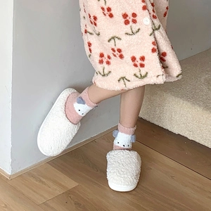 Gros plan de chaussons blancs avec chaussettes ours roses sur parquet en bois