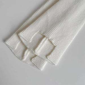 Close-up of white ribbed knit leg warmers showing detailed texture and side slit design
