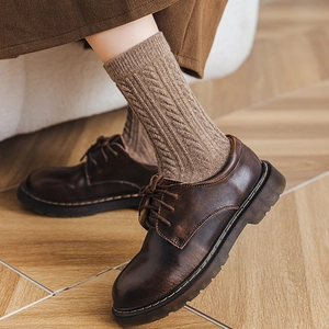 Detailed cable knit texture on khaki mid-calf socks with vintage dark brown leather shoes