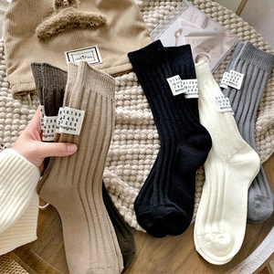 Close-up of thick ribbed knit crew socks with vintage numeric labels in earth tones