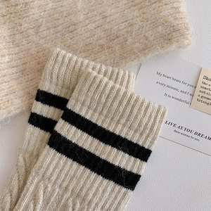 Detailed macro view of cream wool socks with thick knit texture and black double stripes