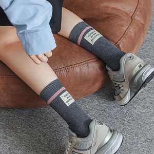 Detail of dark grey ribbed wool socks with pink stripe and white logo tag on ankle