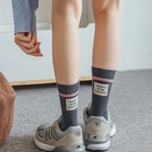Detail of grey wool socks showing the knitted texture, pink stripe, and stylish woven label