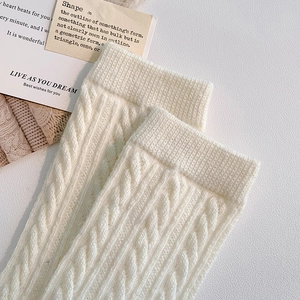 Close-up of beige cable knit socks with ribbed cuffs and warm textured fabric detail