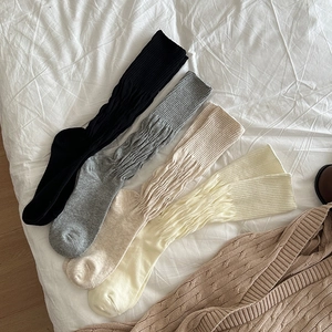 Detail of four pairs of ribbed knit knee-high socks in black, grey, beige, and cream