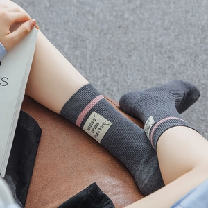 Detail of dark gray wool socks with pink stripes and decorative cloth label