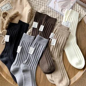 Detailed knit texture of rib-cuffed crew socks in black, grey, brown, khaki, and white