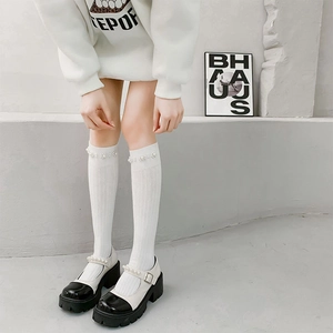 Detail of white knee-high socks with pearl flower accents and black Mary Jane platform shoes