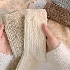 Close-up of thick cable knit texture on warm winter crew socks in earthy tones
