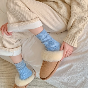 Detail of blue wool blend socks with plush brown suede slippers and warm corduroy pants