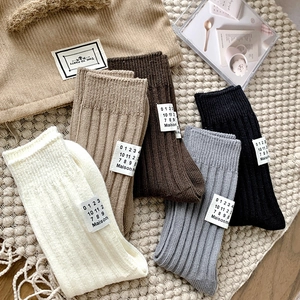 Close-up of five pairs of ribbed knit socks with white Maison labels in various colors