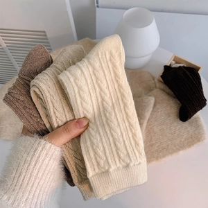 Detailed knit texture and ribbed cuffs of thick cable-knit socks in warm earth tones