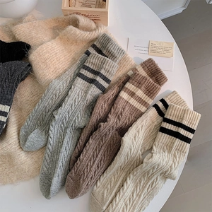 Close-up of three pairs of thick wool socks in grey, brown and beige with cable knit texture