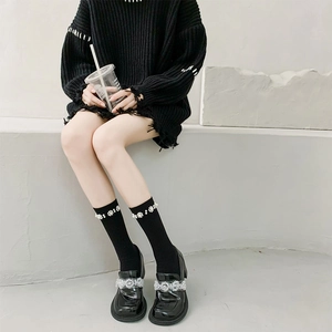 Detail of black patent leather loafers and knit socks with pearl flower embellishments