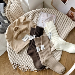 Flat lay of ribbed knit mid-calf socks and beanie with decorative woven labels