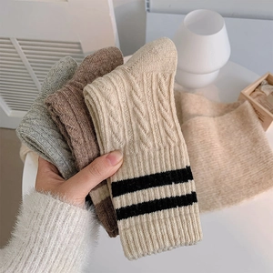 Close-up of thick wool knit socks with cable pattern and sporty stripes in soft textures
