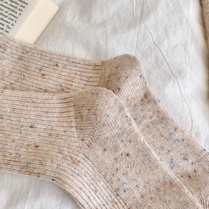 Close-up of beige speckled wool socks with thick vertical ribbed knitting and soft texture