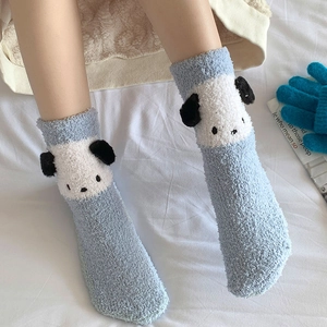 Détail de chaussettes en polaire corail bleu clair avec oreilles 3D sur fond de lit blanc